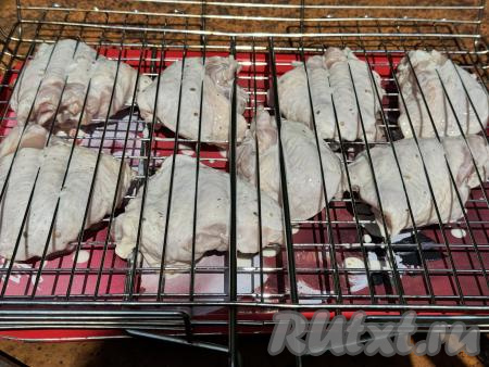 Замаринованные куриные бёдра разложить на решётке для жарки на мангале.