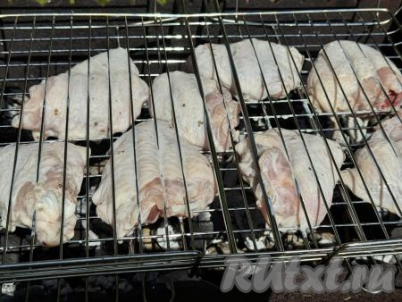 Выложить решётку с курицей на мангал с раскалёнными углями.