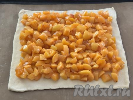 Равномерно разложить на раскатанное тесто абрикосовую начинку, отступая от краёв теста по 2 сантиметра.