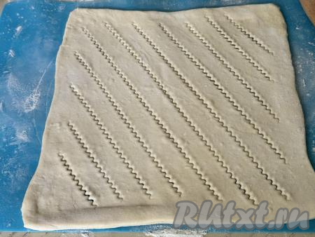 Второй пласт теста на присыпанной мукой поверхности тоже раскатать в квадрат со стороной 25 сантиметров. Сделать на раскатанном тесте разрезы в виде полосок, не дорезая сантиметра по 3 до краёв пласта теста.