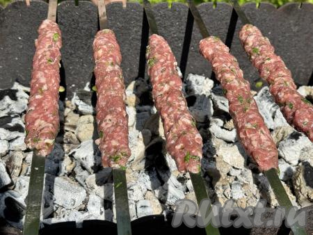 Выложить шампуры с люля-кебабами на мангал с раскалёнными углями. Жар в мангале должен создаваться только прогоревшими углями, прямого огня быть не должно.