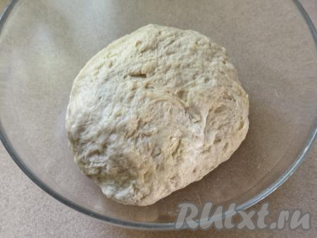 Постепенно подсыпая оставшуюся муку, вымесить тесто руками до гладкого состояния. В общей сложности вымешить руками тесто нужно минут 7. Добавляя муку и вмешивая её, учитывайте, что тесто должно получиться мягким, практически не липнущим к рукам. Оставить колобок из теста в миске, накрыть пищевой плёнкой (или полотенцем), поставить в тёплое место часа на 1,5 (до увеличения в объёме в 2-3 раза). Возможно, муки потребуется чуть больше или чуть меньше, чем указано в ингредиентах, поэтому и не нужно сразу всыпать всю муку. Очень важно в процессе добавления муки ориентироваться на консистенцию замешиваемого теста. 