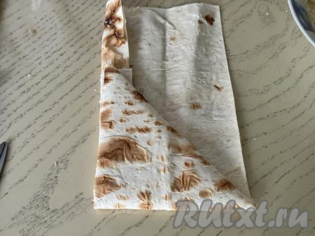 Дальше продолжать заворачивать лаваш с сыром в виде треугольника, повторяя это сворачивание до тех пор, пока не закончится весь прямоугольник из лаваша.