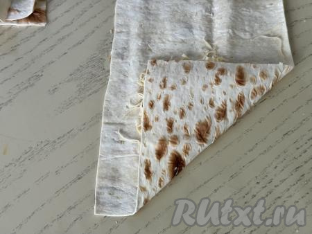 Завернуть край лаваша в виде треугольника, оставив 1,5 сантиметра лаваша не подвёрнутыми, как на фото.