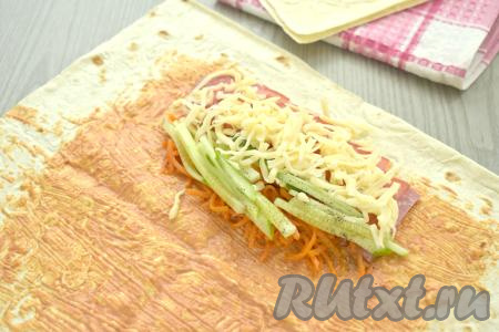 Поверх колбасы и овощей выкладываем половину натёртого сыра.