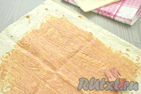 Лаваш я разрезала на 2 половинки, поэтому у меня получились 2 порции шаурмы с копчёной колбасой.&nbsp;Вначале одну половину лаваша расстилаем на столе, смазываем половиной получившегося соуса из майонеза и томатной пасты, отступая от краёв лаваша 3 сантиметра.