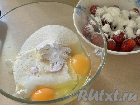 Для приготовления начинки нужно в объёмной миске соединить творог, сырые яйца, сахар и ванильный сахар. В глубокую тарелку выложить 300 грамм подготовленной свежей (или замороженной) клубники, всыпать муку, аккуратно перемешать, обваливая ягоды в муке со всех сторон.