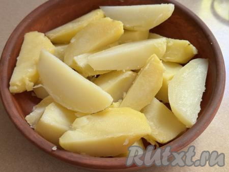 После того как картошка отварится до готовности, слить воду, в которой она варилась. Переложить картофель на тарелку, дать немного остыть, затем нарезать на крупные дольки. Выложить картошку в жаропрочную форму.&nbsp;