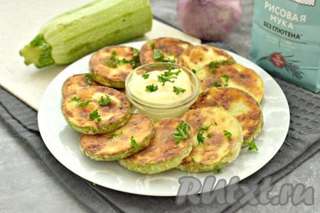 Кабачки, жареные в рисовой муке, с бумажных полотенец перекладываем на тарелку, посыпаем мелко нарезанной зеленью и, дополнив соусом (у меня - соус из майонеза и чеснока), подаём к столу. Кабачки получились вкусными, покрытыми аппетитной, мягкой корочкой снаружи, и нежными внутри.