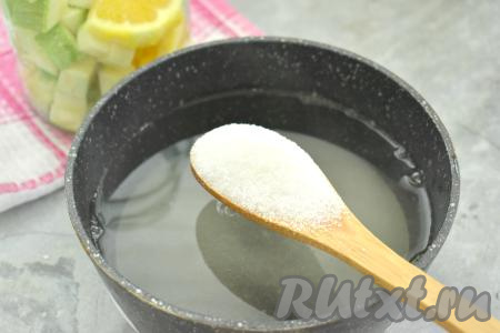 Через 15 минут воду из банки сливаем в кастрюльку, оставляя апельсины и кабачки в банке. Очень удобно сливать воду, надев на баночку капроновую крышку с отверстиями. Банку, после того как из неё слили воду, сразу прикрываем прокипячённой крышкой. В кастрюлю с водой, слитой из банки, всыпаем сахар, перемешиваем и на сильном огне доводим до кипения, затем провариваем сироп минуты 2 (до полного растворения сахара).