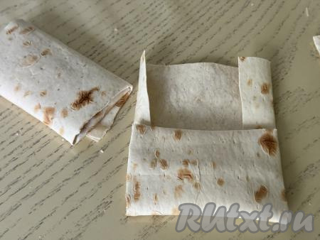 Начиная от узкой стороны лаваша с начинкой, завернуть лаваш в виде конвертика, сделав несколько оборотов.