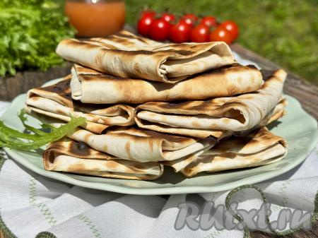 Готовые конвертики из лаваша переложить на тарелку и подать в горячем виде.