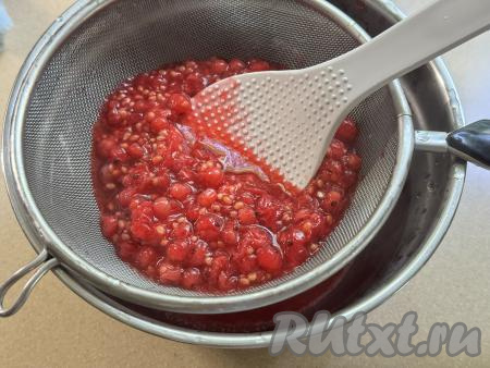 Взять миску, поверх неё поставить сито. Откинуть проваренную ягодную массу на сито и с помощью лопатки (или столовой ложки) перетереть смородину через сито в миску. В результате в миске будет пюре без косточек из красной смородины, а в сите останется практически сухой жмых с косточками (этот жмых нам не понадобится).