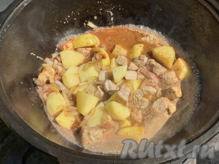 Затем влить воду, перемешать картошку со свининой.