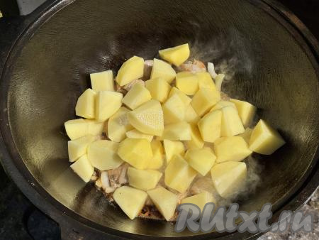 В казан со свининой и луком добавить дольки картошки.