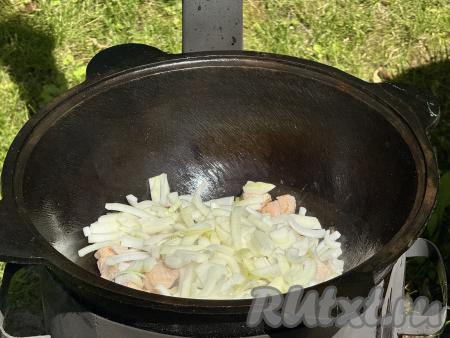 Добавить лук в казан с обжаренной свининой.