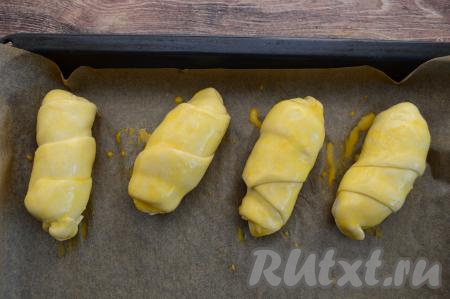 Сырое яйцо в небольшой ёмкости взболтать вилкой до однородности. Смазать взбитым яйцом каждую булочку.