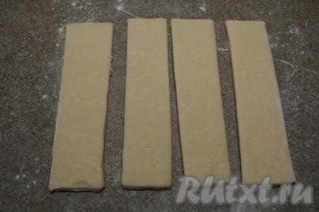 Пласт слоёного теста, не раскатывая, на слегка присыпанной мукой поверхности разрезать на 4 одинаковых полоски.