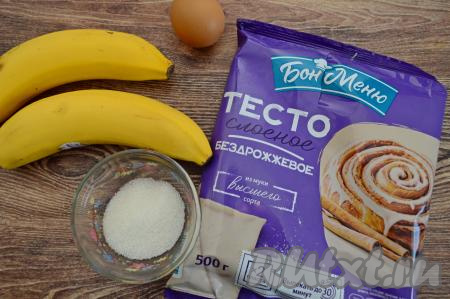Подготовить продукты для приготовления булочек с бананом. Слоёное тесто нужно заранее разморозить при комнатной температуре. Слоёное тесто для этой выпечки можно взять как дрожжевое, так и бездрожжевое. Бананы лучше выбирать спелые, сладкие, можно даже слегка переспелые.