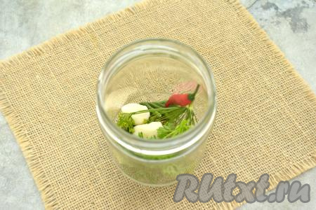 Следом добавляем в каждую банку по маленькому стручку жгучего перца и по 2 зубчика чеснока.