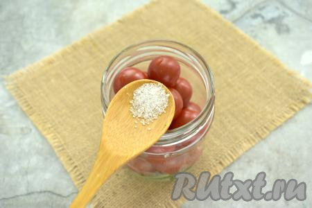 По прошествии 10 минут снова воду из банок сливаем в кастрюлю. В каждую банку с помидорами черри всыпаем щепотку лимонной кислоты. Прикрываем банки крышками.