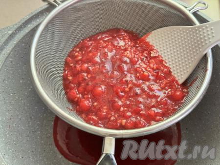 Периодически перемешивая, довести ягоды до кипения, уменьшить огонь и варить 2 минуты, чтобы смородина стала мягкой. Затем взять кастрюлю с толстым дном, поверх неё поставить сито, выложить в него проварившиеся ягоды красной смородины. С помощью лопатки (или столовой ложки) перетереть смородину через сито в кастрюлю. В результате перетирания в сите останутся практически сухие косточки и шкурки, их можно будет выбросить. 