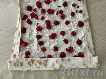 Немного подвернуть вначале боковые края лаваша на начинку, а затем, начиная с более узкого края, свернуть лаваш с творожно-ягодной начинкой в рулет.&nbsp;