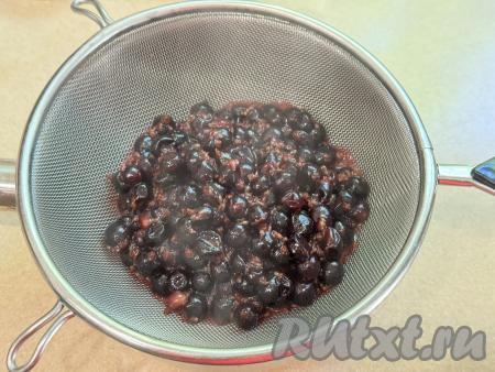 Взять небольшую кастрюльку с толстым дном, поверх неё поставить сито. Выложить в сито проварившуюся чёрную смородину. Столовой ложкой перетереть смородину через сито. В результате перетирания в кастрюльке будет однородное смородиновое пюре. В сите останутся практически сухие косточки и шкурки, их можно выбросить.