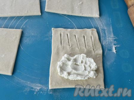 На край прямоугольника без надрезов выложить 2 чайных ложки рикотты, немного разровнять, отступая от краёв 1-1,5 сантиметра.