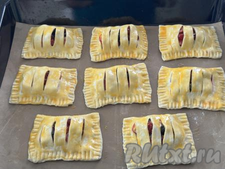 Яичный желток в небольшой ёмкости взбить вилкой до однородности. Смазать слойки взбитым желтком и поставить противень в разогретую до 200 градусов духовку.