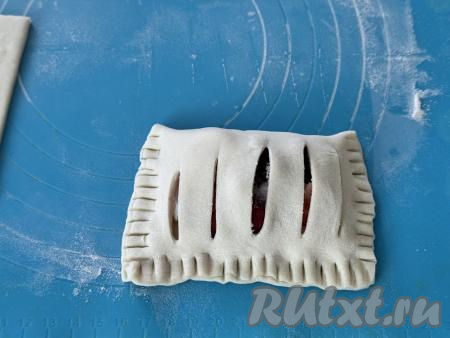 Накрыть начинку стороной теста с надрезами и хорошо скрепить края слойки. Я скрепила края вилкой. Чтобы вилка не приставала к тесту, можно зубчики окунать периодически в муку.
