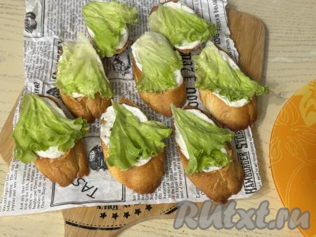 Листья салата вымыть, обсушить, выложить на кусочки багета поверх соуса.