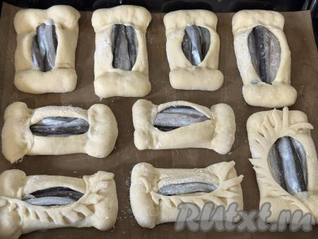 А затем немного подвернуть более короткие края овала на рыбку, прижимая края теста пальцами. Сформированный открытый пирожок с мойвой выложить на противень, застеленный пергаментом (или ковриком) для выпечки.&nbsp;Аналогично сформировать ещё 8 пирожков с рыбкой, выкладывая их на застеленный противень на небольшом расстоянии друг от друга.
