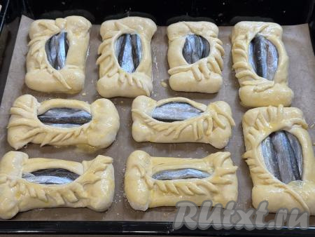Оставшееся тесто раскатать, вырезать из него украшения, выложить на пирожки. Оставить пирожки при комнатной температуре минут на 25, чтобы дрожжевое тесто подошло. Яичный желток в небольшой ёмкости взбить вилкой. По прошествии 25 минут смазать все пирожки взбитым желтком.