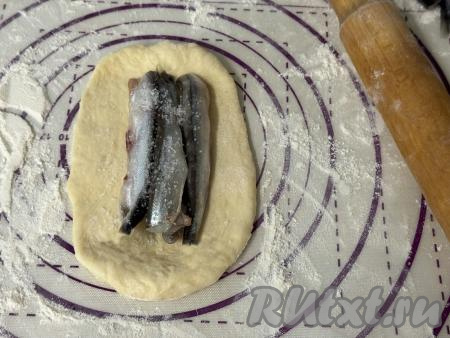 Разделить тесто на 10 частей. У нас получатся 9 пирожков с мойвой и одну часть теста будем использовать для формирования украшения. Каждую часть теста слегка раскатать скалкой в овал, выложить в середину 3-4 рыбки.