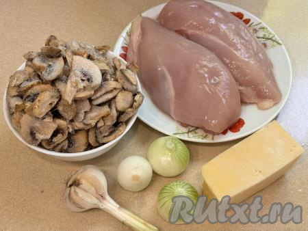 Подготовить продукты для приготовления рулетиков из куриного филе с грибами и сыром в духовке. Лук и чеснок почистить. Куриное филе промыть водой, обсушить. Для этого блюда можно взять предварительно отваренные в течение 25-30 минут лесные грибы или шампиньоны. Я использовала уже нарезанные замороженные шампиньоны. Можно будет готовить и со свежими шампиньонами, их нужно будет промыть водой, нарезать на пластины. 