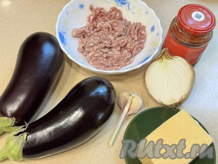 Подготовить продукты. Баклажаны вымыть. Для того чтобы блюдо было удобно формировать слоями, баклажаны желательно брать одинакового размера. Лук и чеснок почистить. Фарш для этого блюда можно взять как покупной, так и приготовленный в домашних условиях. Для этого блюда подойдёт свиной, говяжий, куриный, индюшиный или смешанный из нескольких видов мяса фарш. Для получения фарша я взяла кусочек свинины и пропустила его через мясорубку.