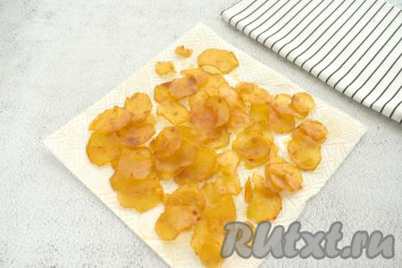 После сушки чипсы из картофеля рекомендуется выложить на бумажные полотенца, чтобы удалить лишнее масло.