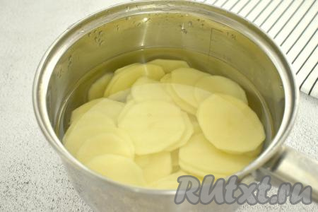 Кружочки картофеля перекладываем в кастрюлю, заливаем полностью водой и ставим на сильный огонь. После закипания варим картошку буквально 3-5 минут (не больше) на минимальном огне. Если картошку не отварить, а оставить сырой, то чипсы в сушилке станут чёрными, а на вкус - сырыми.