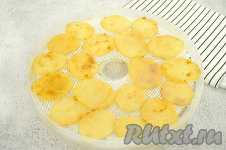 Застилаем поддоны для сушилки специальными силиконовыми сетчатыми ковриками (или силиконизированным пергаментом, его можно приобрести в любом продуктовом магазине).&nbsp;Раскладываем подготовленные кружочки картофеля в один слой на застеленный поддон сушилки. Мне потребовались 3 поддона диаметром 24 сантиметра.