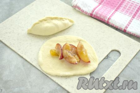 Начинку из слив зрительно делим на 7 равных частей (по количеству пирожков, которые мы планируем лепить). В центр лепёшки из слоёного теста выкладываем часть сливовой начинки. Скрепляем края лепёшки над начинкой, формируя пирожок. Постепенно лепим все 7 слоёных пирожков со сливами.