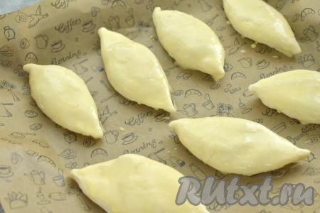 Пирожки выкладываем "швом" вниз на противень, застеленный ковриком (или пергаментом) для выпечки. В небольшую ёмкость выкладываем яичный желток, вливаем 1 столовую ложку молока, взбиваем вилкой до однородности, затем получившейся смесью смазываем поверхность пирожков.