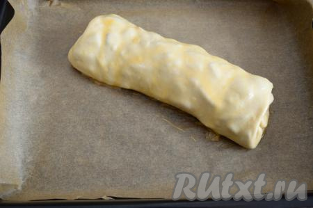 В небольшую ёмкость разбить яйцо, взболтать его вилкой до однородности, а затем получившейся яичной смесью с помощью силиконовой кисточки смазать поверхность штруделя.