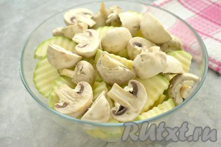 Моем шампиньоны, убирая с них загрязнения. Нарезаем грибы достаточно крупно. У меня были средние по размеру шампиньоны, поэтому я разрезала их пополам.&nbsp;Добавляем грибы в миску с картошкой и кабачками.