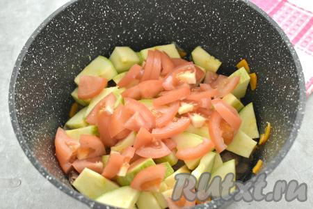 Помидоры моем, по желанию, очищаем от кожуры. Нарезаем помидоры на небольшие ломтики и тоже перекладываем к куриным сердечкам с овощами.