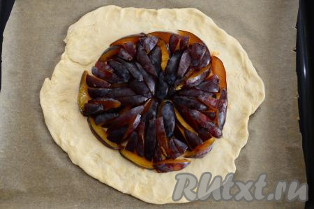 Слоёное тесто, растянутое в круг, переложить на противень, предварительно застеленный пергаментом. В центр растянутого круга, отступая от краёв теста по 3 сантиметра, выложить сливы, стараясь разместить их кожурой вверх в виде круга. Сливовую начинку советую размещать именно по кругу, тогда галета будет особенно аппетитной.