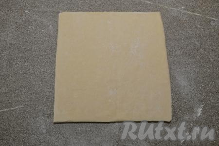 На рабочую поверхность, немного посыпанную мукой, выложить разморозившееся слоёное тесто.