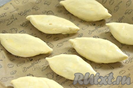 На противень, застеленный пергаментом (или ковриком) для выпечки, выкладываем сформированные слоёные пирожки с грибами "швом" вниз. В небольшой ёмкости вилкой взбиваем до однородности яичный желток, получившейся яичной смесью смазываем пирожки. Противень с пирожками отправляем в духовку, разогретую до 200 градусов.