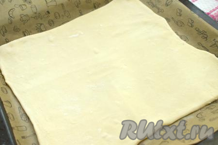 Размороженный пласт слоёного теста выкладываем на присыпанный мукой стол, раскатываем его до квадрата со стороной около 29 сантиметров. Раскатанное тесто сразу перекладываем на противень, застеленный пергаментом (или ковриком для выпечки).