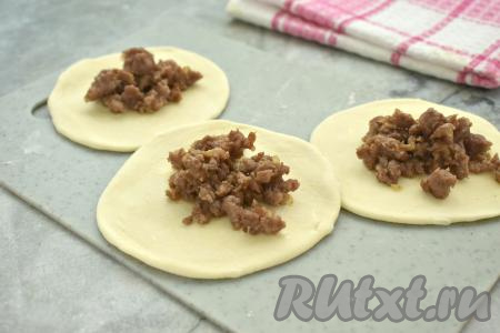 Раскатываем&nbsp;кусочки теста&nbsp;в лепёшки диаметром около 10-11 сантиметров. В центр каждой лепёшки кладём 1 столовую ложку остывшей начинки из фарша и лука.